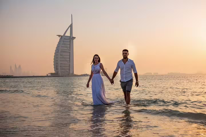 Couple walking in the sea at sunset with Burj Al Arab view on a Dubai private tour with photographer