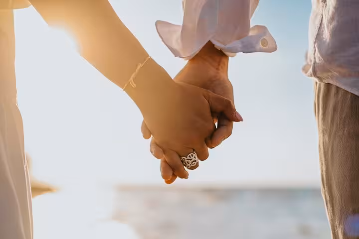 Couple holding hands at sunset during a private photoshoot in Agios Nikolaos, capturing a romantic seaside moment.