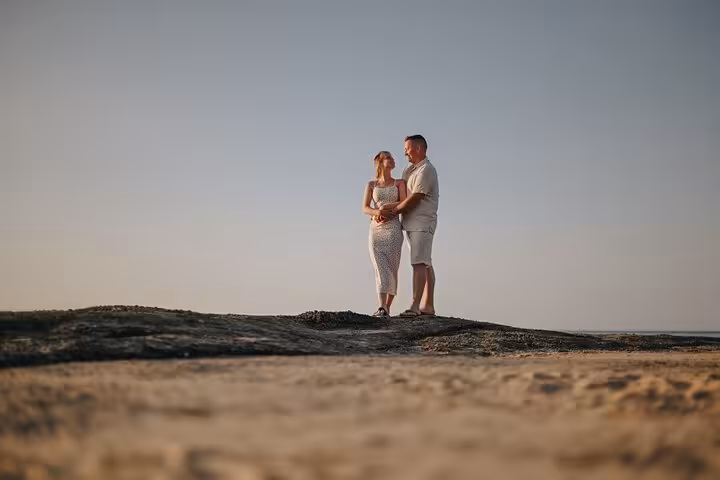 Couple embracing on a scenic rocky shore during a private photoshoot in Gouves at sunset.