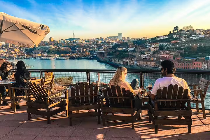 Couple relaxing with drinks overlooking scenic Porto views during the Walking Sunset Tour Port Wine Rooftop Private.
