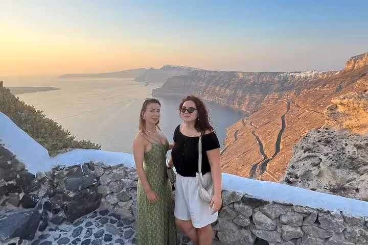 Couple at Santorini caldera viewpoint at sunset, perfect stop on private wine tour with tapas and 3 wineries