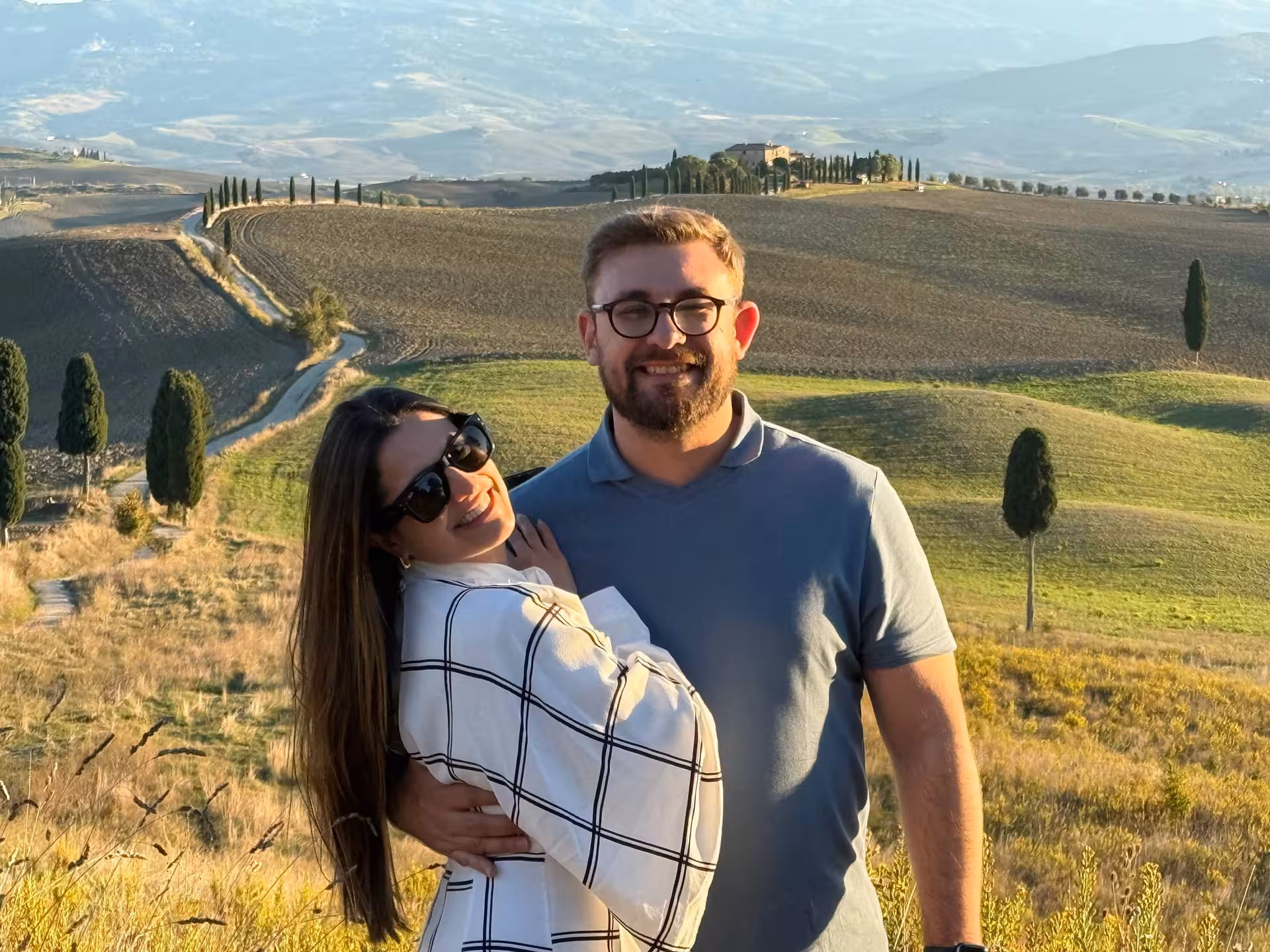 Couple enjoying a picturesque sunset over Tuscany's rolling hills near Pienza on a day trip.
