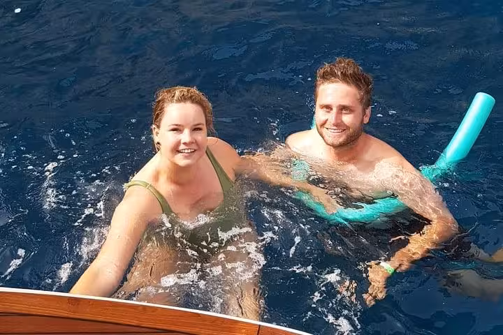 Couple enjoying a swim in the clear waters of Capri on a small group boat excursion from Sorrento.