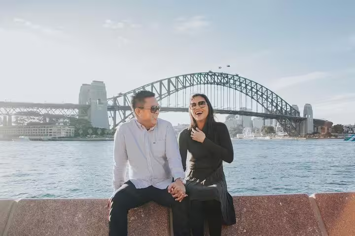 Couple laughing by Sydney Harbour with Harbour Bridge backdrop on a private personal travel photographer tour