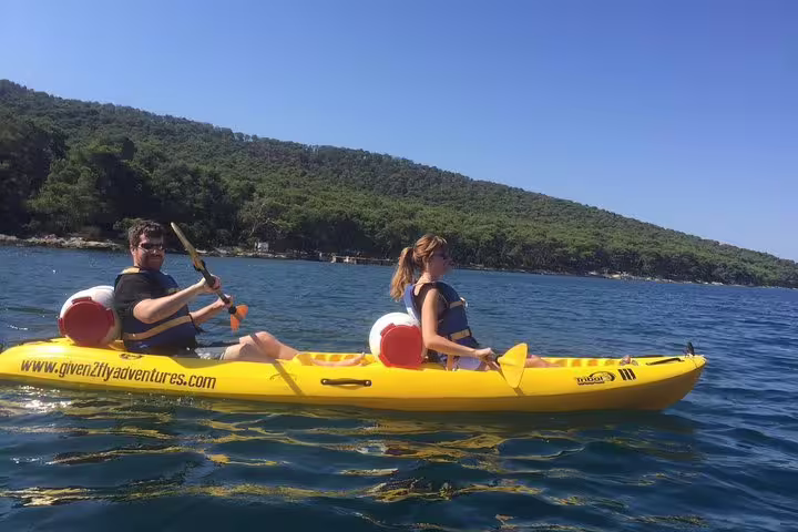 Couple paddling a tandem kayak near Split coastline, Adriatic sea kayaking and snorkeling tour in Croatia