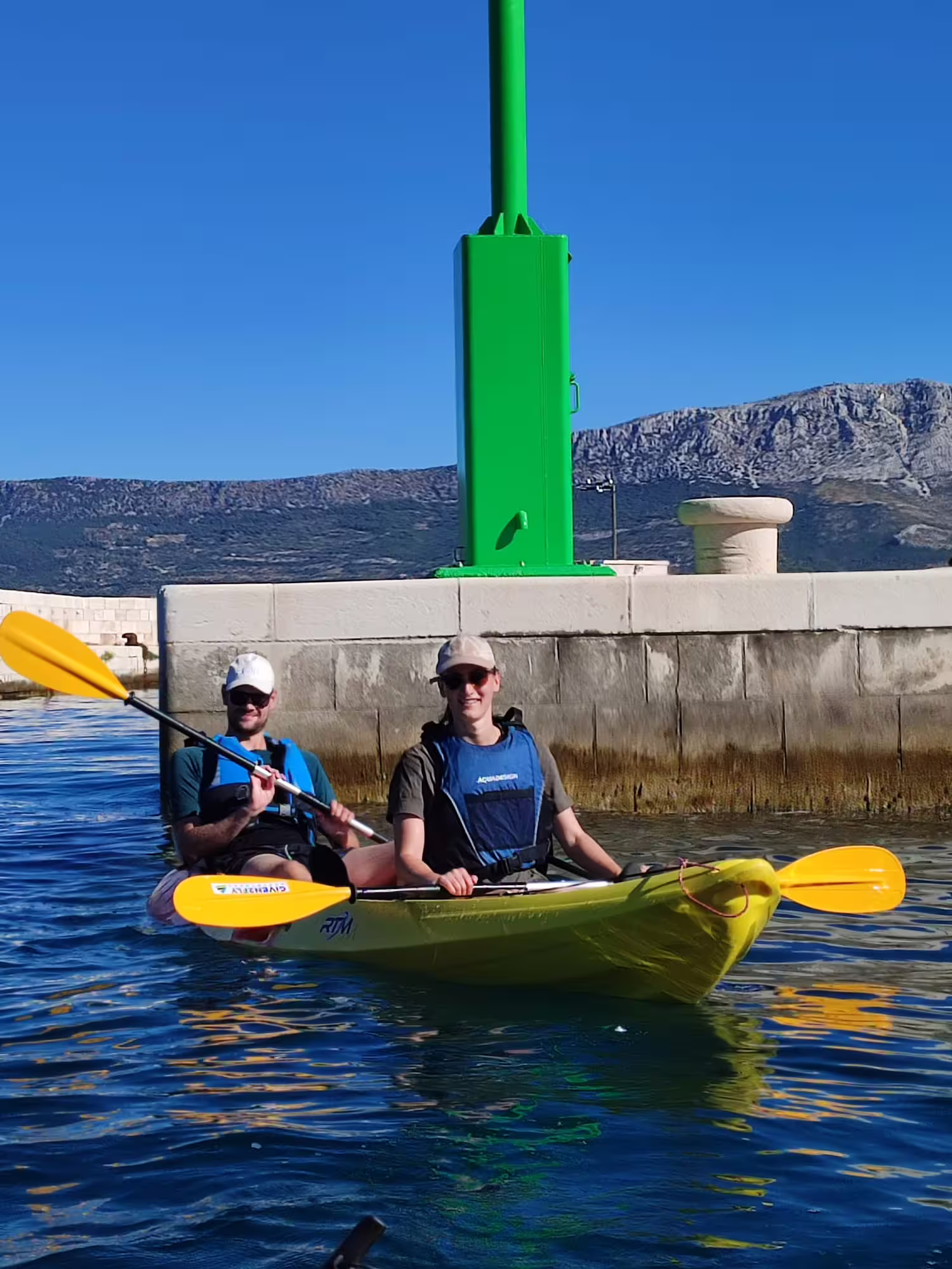 Couple in tandem kayak by Split harbor breakwater and green lighthouse, Adriatic sea kayaking and snorkeling tour