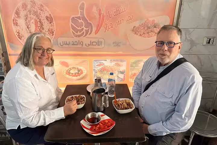 Couple tasting Egyptian street food at a Cairo café during a private Cairo food tour and funny walking tour