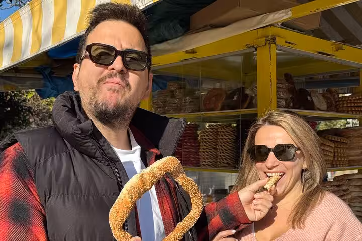 Couple tasting sesame koulouri at an Athens street bakery on a traditional Greek food tour