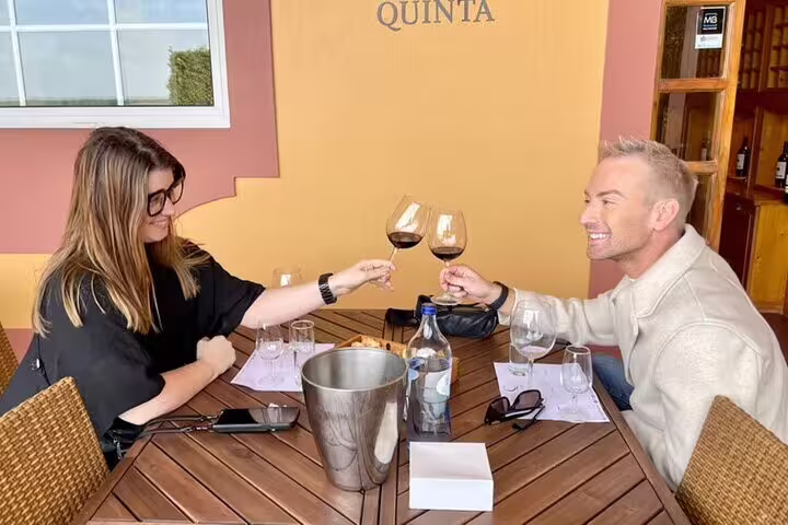 Couple toasting with red wine at a rustic Quinta during the Setúbal and Arrábida all-inclusive food and wine tour from Lisbon.