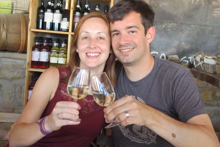Smiling couple toasting with wine glasses at a Tuscan winery, highlighting Florence's vineyard experiences.