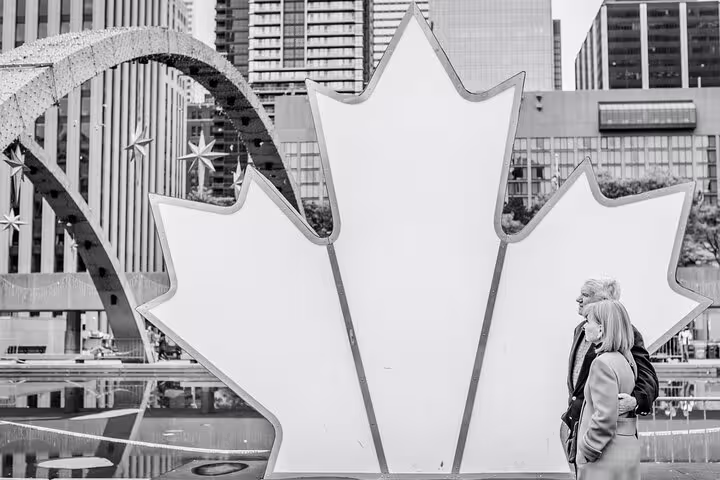 Couple poses by Toronto City Hall maple leaf sign on a private tour with personal travel photographer