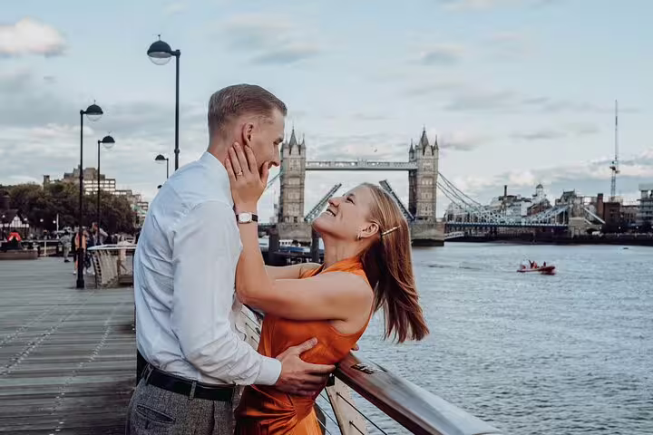 Couple embracing on a riverside boardwalk with Tower Bridge in the background during a London photography tour.