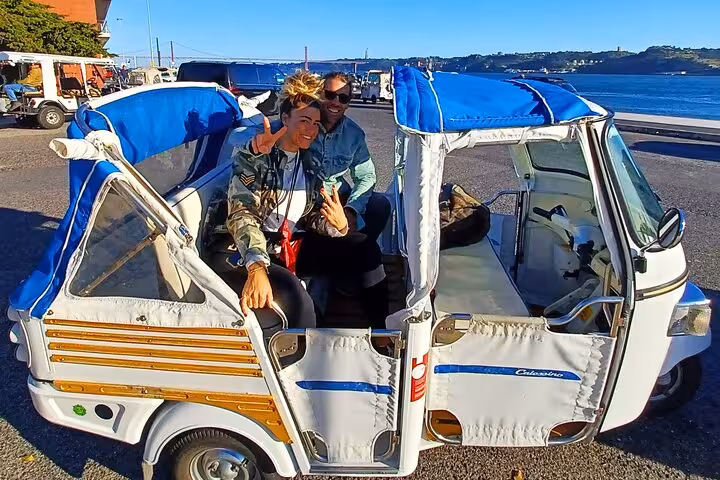 Couple riding a tuk tuk in Belém Lisbon on a private 2-hour tour, scenic waterfront route and pastries