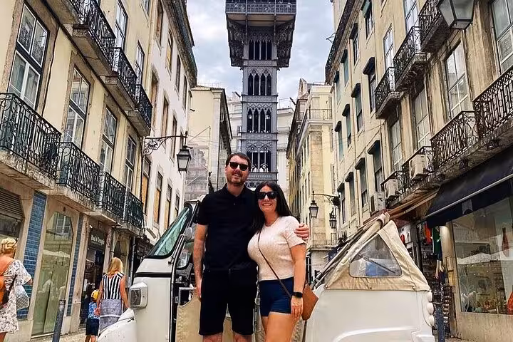 Couple posing by tuk tuk on Rua Augusta under Santa Justa Lift, 2-hour private historic Lisbon tour