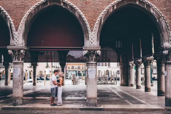 Couple posing under Venetian arches at Rialto, captured on a private travel photographer tour in Venice
