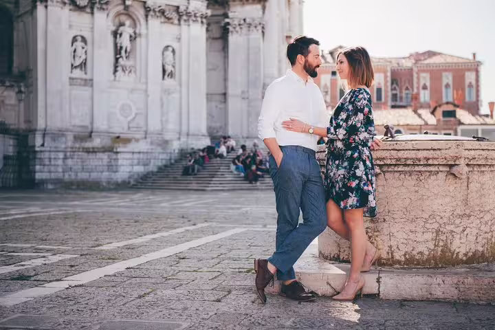 Couple posing by Venetian canal bridge near historic church, private travel photographer tour in Venice