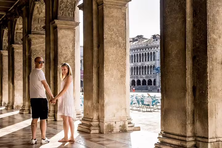 Couple holding hands under historic arches in Venice during a private photo shoot walking tour.