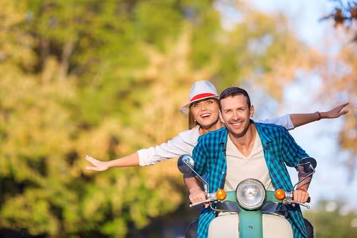 Couple joyfully riding a Vespa through scenic Florence, embodying adventure and romance on an Italian scooter rental.