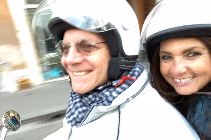 Couple enjoying a Vespa ride during a private guided tour of Rome's iconic sights.