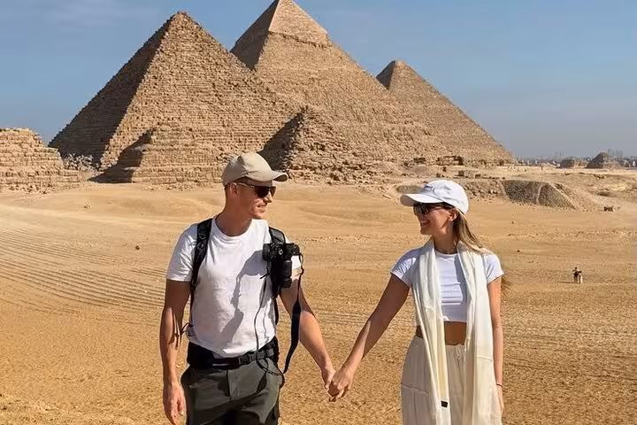Couple walking by the Giza pyramids in Cairo on a Giza Pyramids Saqqara Memphis day tour from Cairo