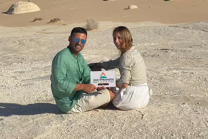 Couple sitting on chalk rock in Egypt White Desert during 2-day Black & White Desert tour with jeep and camp