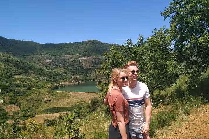 Couple posing with a scenic view of lush hills and a serene lake on the Grand Wine Tasting & Food Tour in Berat.