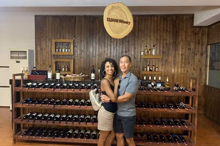 Happy couple embracing in Luani Winery, Berat, amidst rows of fine wine bottles, capturing the joy of wine tasting.
