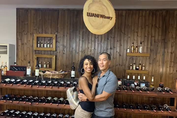 Couple enjoying wine tasting at Luani Winery in Berat, surrounded by a rustic display of local wines.