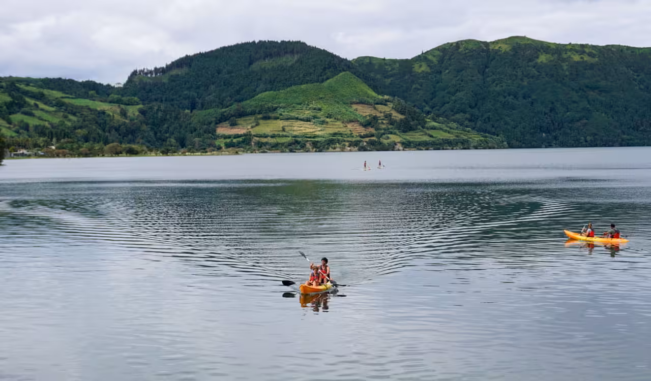 Couples kayaking on calm Sete Cidades crater lake with green mountains, part of a guided half-day jeep and kayak tour