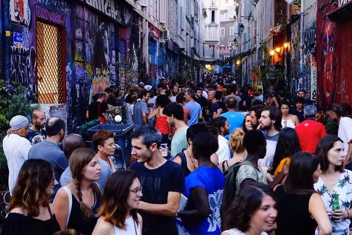 Crowded graffiti-lined alley in Cours Julien Marseille, lively street art vibe on Noailles market tour