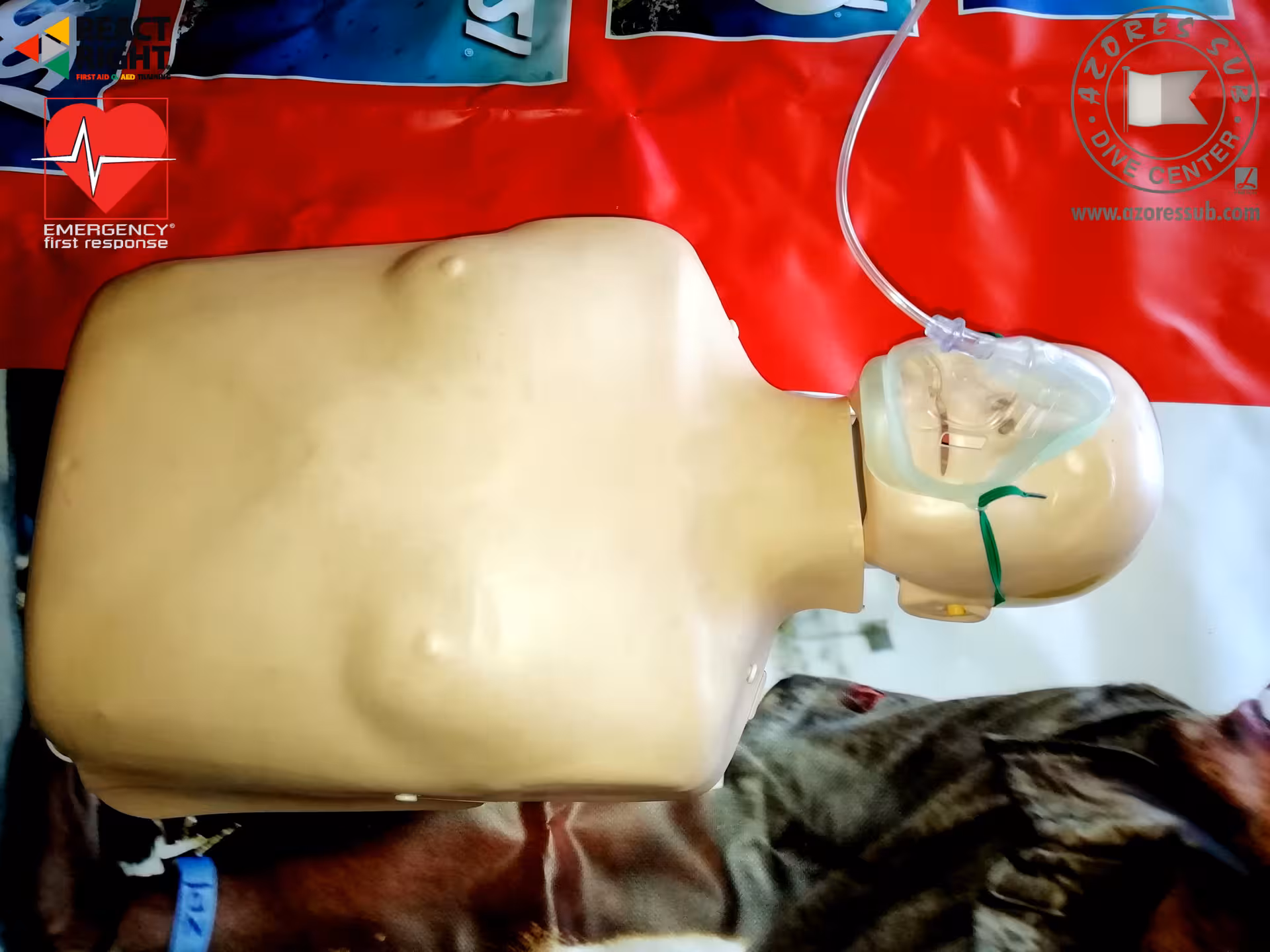 Close-up CPR manikin wearing oxygen mask and tubing, demonstrating emergency oxygen delivery in first aid training