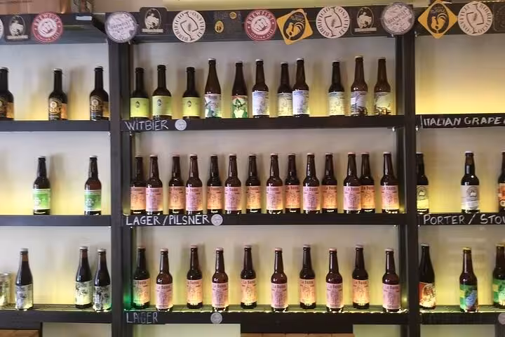 A wall of craft beer bottles displayed in a Rome bar, highlighting various styles for the Art & Craft Beer Tour.
