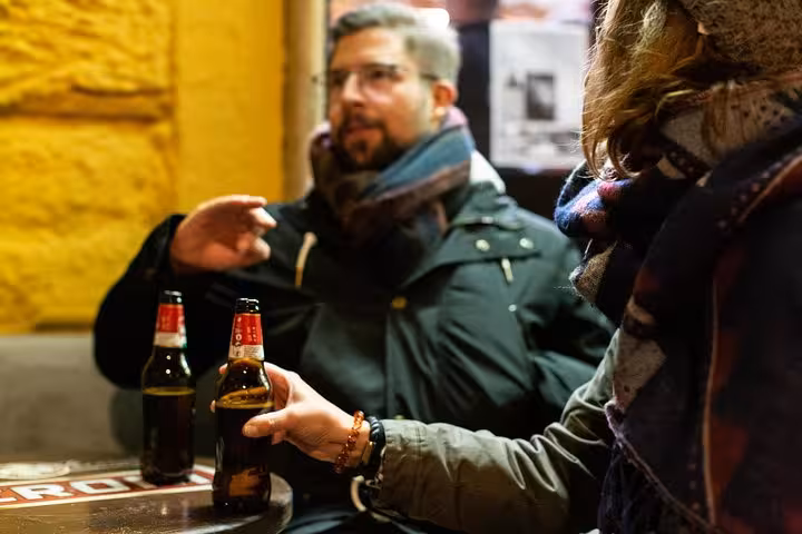 Two people enjoying craft beers in a cozy Roman bar during a local beer tour.