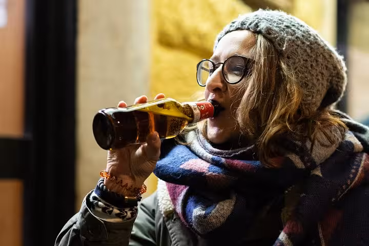 Person enjoying a bottled craft beer during an evening on the Local Craft Beer Walk in Rome.