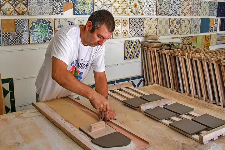 Craftsman creating tiles in Azeitao, showcasing traditional Portuguese artistry on a small group tour.