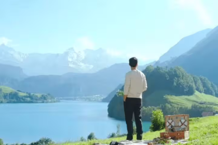 Visitor overlooks a serene Swiss lake and majestic mountains, capturing the essence of the Crash Landing on You tour in Switzerland.