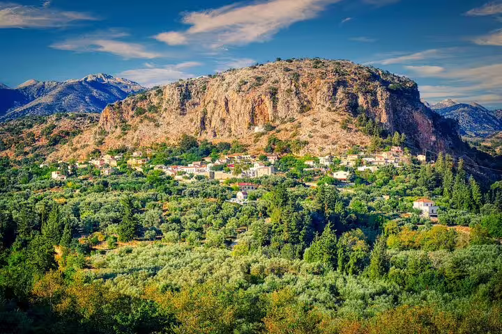 Charming Cretan village nestled in lush greenery below rocky cliffs, a highlight of Apokoronas private tours.