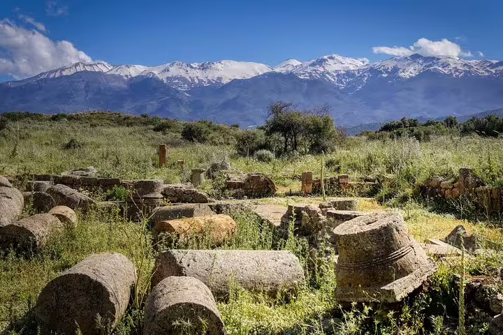 Ancient ruins in a lush Cretan landscape with snow-capped mountains, ideal for Apokoronas private village tours.
