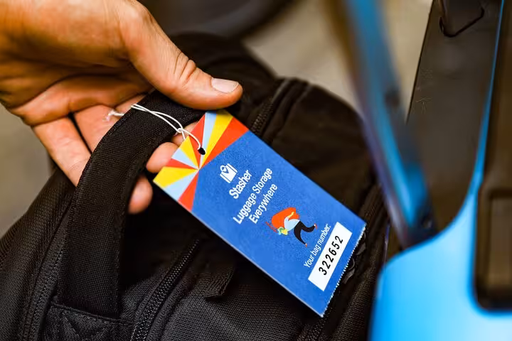 Hand attaching luggage storage tag to backpack for Crete Chania Old Harbour secure bag drop service