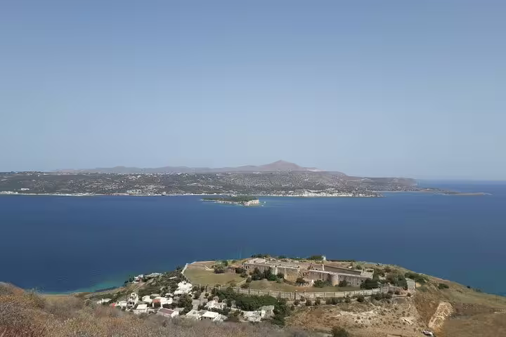 Breathtaking aerial view of Crete's coastline with azure sea and distant hills under a clear blue sky.