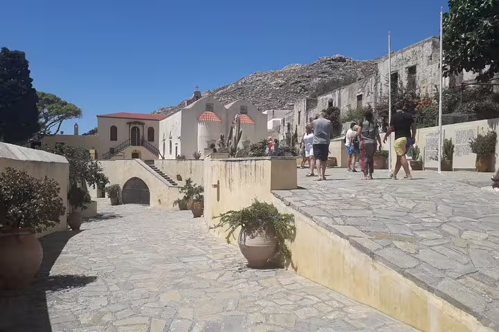 Tourists enjoy the historic charm and scenic beauty of a sunlit courtyard on Crete's south coast during a private tour.
