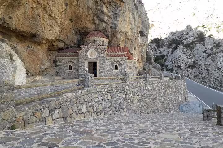Historic stone chapel nestled against rocky cliffs on the scenic South Coast of Crete, perfect for cultural exploration.