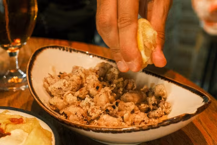Savoring crispy calamari with a squeeze of lemon on the Gràcia Catalan food tour in Barcelona.