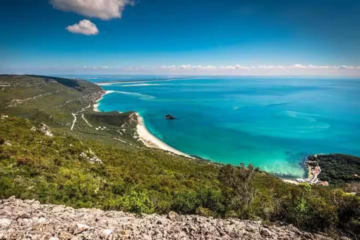Stunning panoramic view of Arrábida's lush green hills and turquoise coastline, ideal for private tours in Portugal.