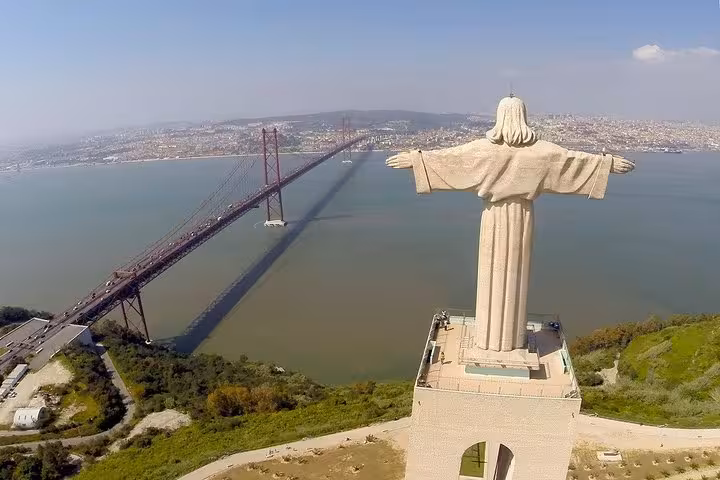 Aerial view of Cristo Rei statue overlooking the Tagus River and iconic 25 de Abril Bridge in Lisbon, Portugal.