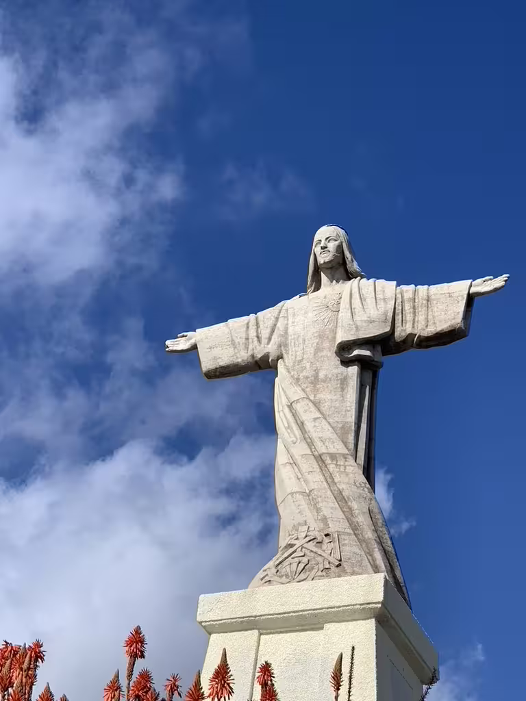 Majestic Cristo Rei statue under a blue sky, a highlight of the East side Pico do Arieiro and Santana full-day tour.