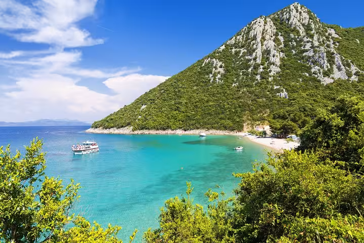 Turquoise Adriatic bay and beach beneath green cliffs, Croatia private tour with island cruise experience