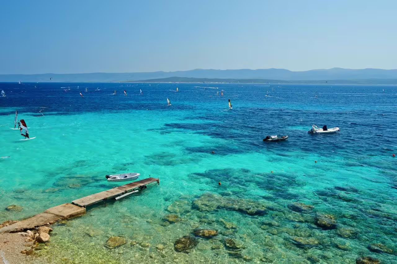 Turquoise Adriatic Sea with boats and windsurfers, Croatia group adventure tour featuring coastal views and swims