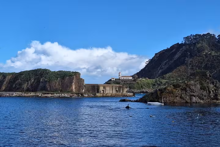 Scenic view of Cudillero's rocky coastline with clear blue skies, ideal for the Cudillero, Aviles, and Cabo Peñas tour.