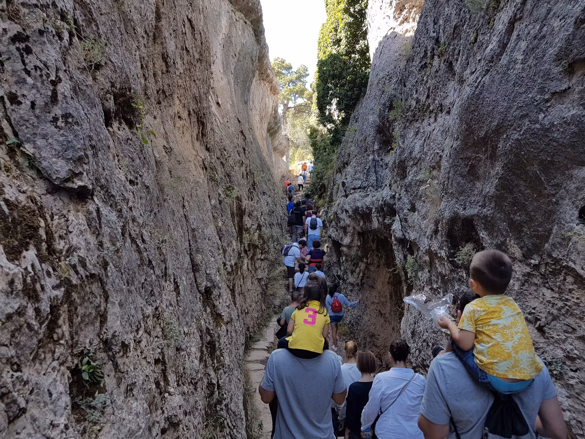 Visitors walking through a narrow rock corridor in the Enchanted City, Cuenca, on a day trip from Madrid